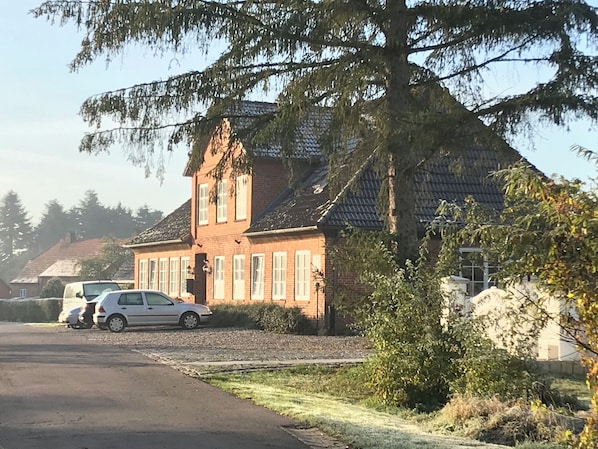 A two-story brick house with a sloped roof, a driveway, and a parked car. - New Listing (Altenkrempe)