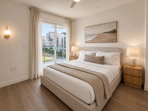 A bedroom with a large bed, two bedside lamps, a painting, and a view through a sliding glass door. - Ocean-View Penthouse near Beach w/ Rooftop Deck & Pool (Santa Monica)