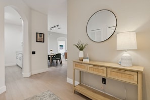 A modern interior with a wooden console table, a round mirror, and a white lamp. - Palm Haven- Spacious 3BR Condo in Windsor Palms Resort (Kissimmee)