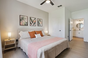 A bedroom with a bed, bedside lamps, a nightstand, and a door leading to a bathroom. - Palm Haven- Spacious 3BR Condo in Windsor Palms Resort (Kissimmee)