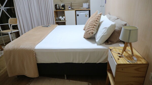 A hotel room with a bed, bedside lamp, and a small wooden table with a lamp.