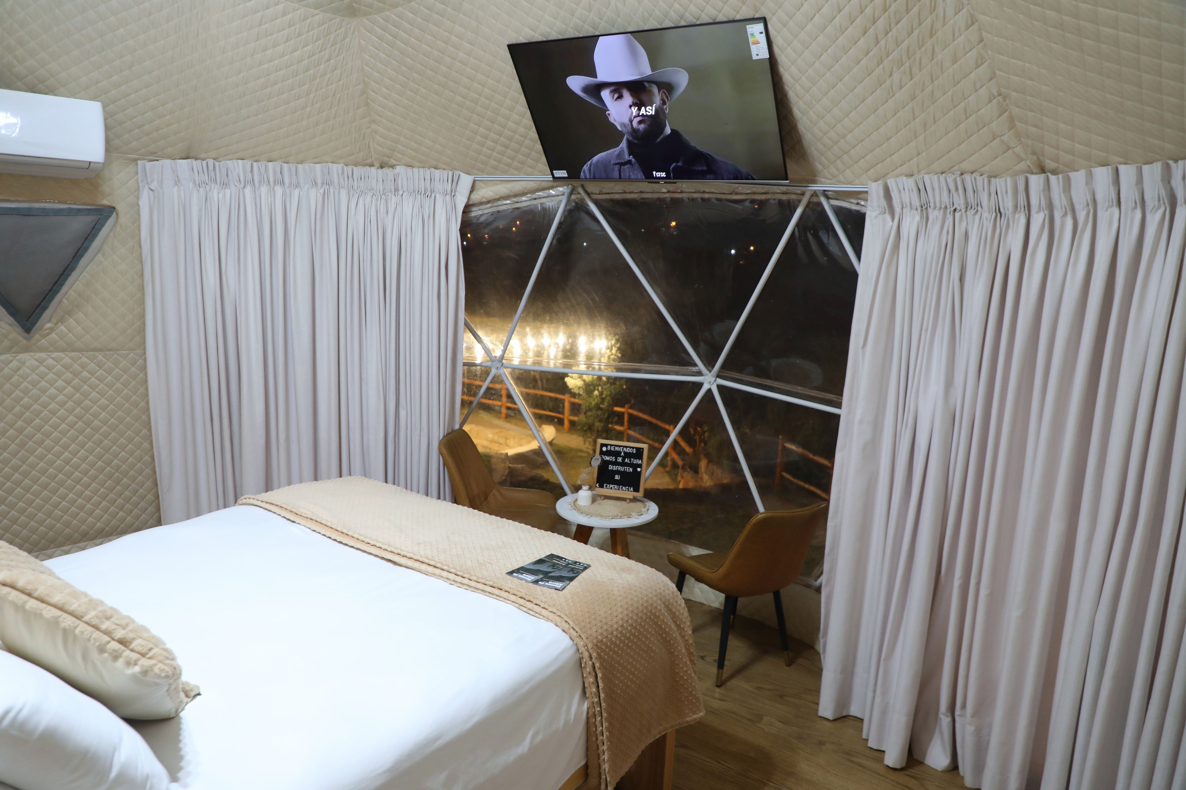 Quarto com cama, mesa e janela com cortinas.