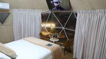 Quarto com cama, mesa e janela com cortinas.