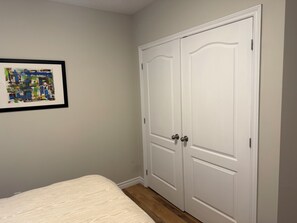 Une chambre à coucher avec un lit, une porte blanche et un tableau encadré au mur.