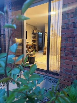 Een modern huis met een bakstenen gevel, een glazen deur die leidt naar een interieur met een boekenkast en een eethoek.