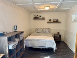 Ein Schlafzimmer mit einem Bett, einem Nachttisch, einer Ablage mit Flaschen und einer kleinen Pflanze.