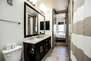 Une salle de bain moderne avec un grand miroir, deux vasques et des toilettes.