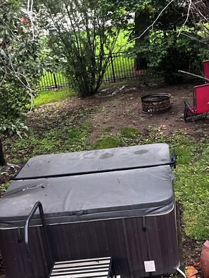 A black suitcase in a yard with a metal bench, a red chair, and a metal container. - SanT Village 3-bedroom house in Brookings (Brookings)