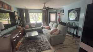 A living room with a sofa, a coffee table, a TV, and a ceiling fan. - SanT Village 3-bedroom house in Brookings (Brookings)