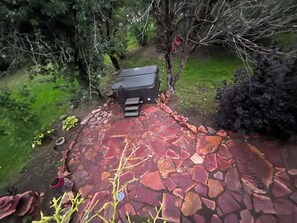 Eine Terrasse mit Grill, Steinboden und umgebendem Grün.
