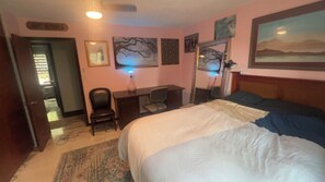 Ein Hotelzimmer mit Bett, Schreibtisch, Stuhl und einem Bild an der Wand.