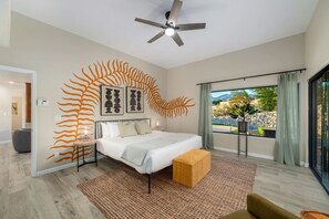Primary bedroom with king bed, en-suite bathroom, walk-in closet, and private patio with access to the gorgeous backyard
