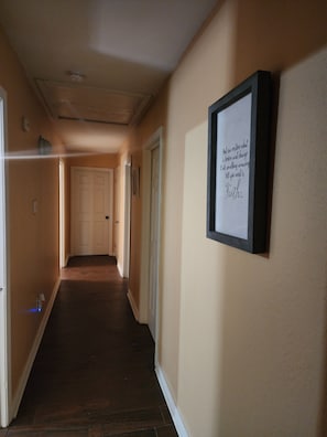A hallway with a framed inspirational quote on the wall, a door at the end, and a light switch on the wall. - The Southern Spot (Baton Rouge)