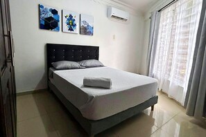A bedroom with a bed, a headboard, and three wall-mounted artworks. - El Caney Living (Cali)