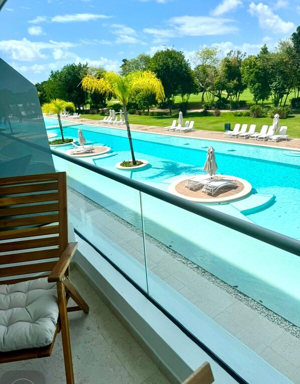 A poolside view with a lounge chair, a pool, and a grassy area with trees. - Paradise in Punta Cana (Higuey)