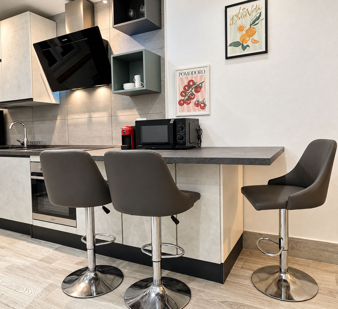 A modern kitchen with a flat-screen TV, a microwave, and bar stools.