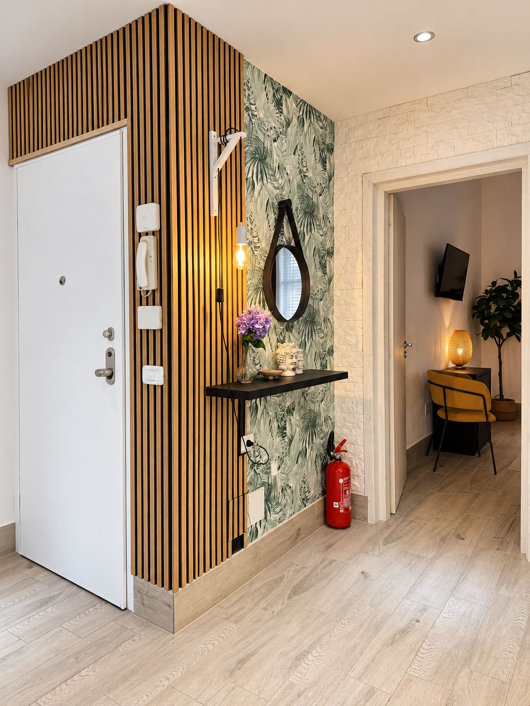 A modern interior with a wooden panel wall, a mirror, a shelf with decorative items, a fire extinguisher, and a television mounted on the wall.