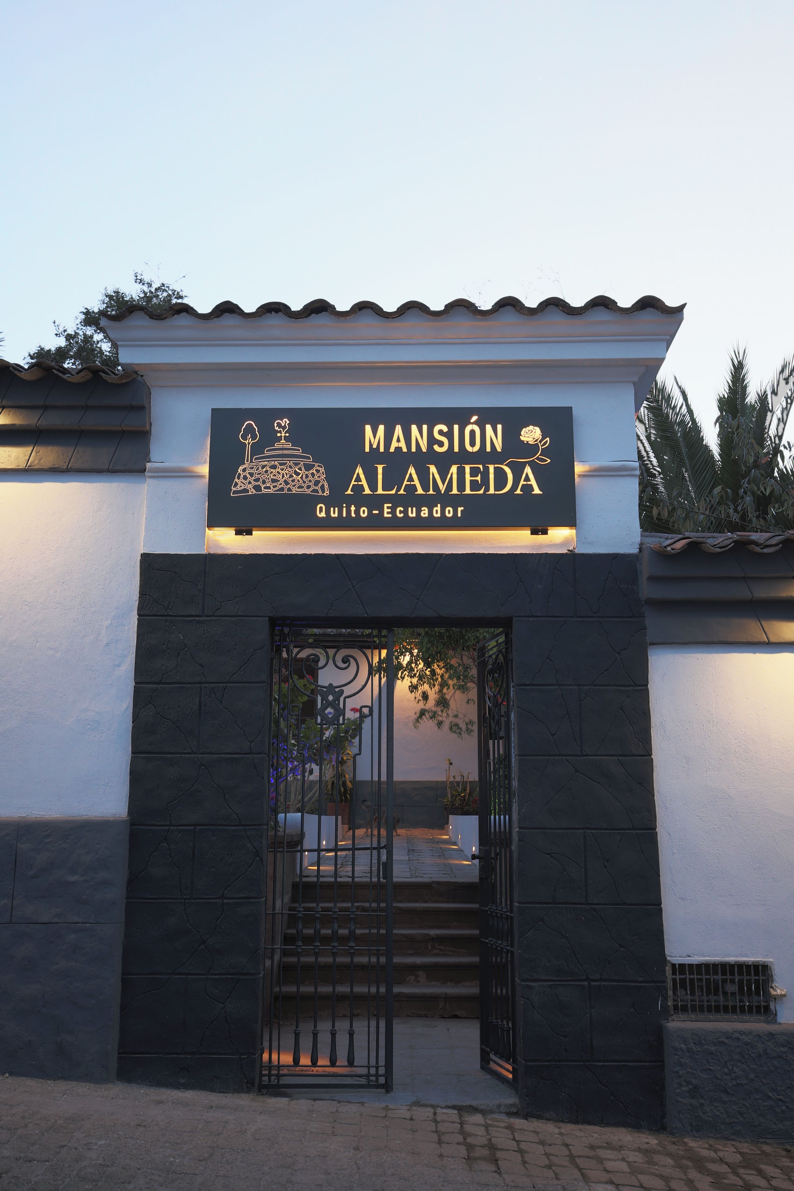 Entrada de un hotel con un letrero que dice 'MANSIÓN ALAMEDA Quito-Ecuador'.