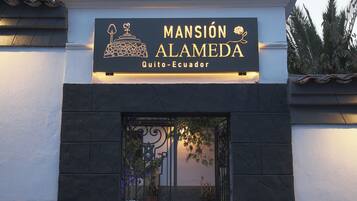 Entrada de un hotel con un letrero que dice 'MANSIÓN ALAMEDA Quito-Ecuador'.