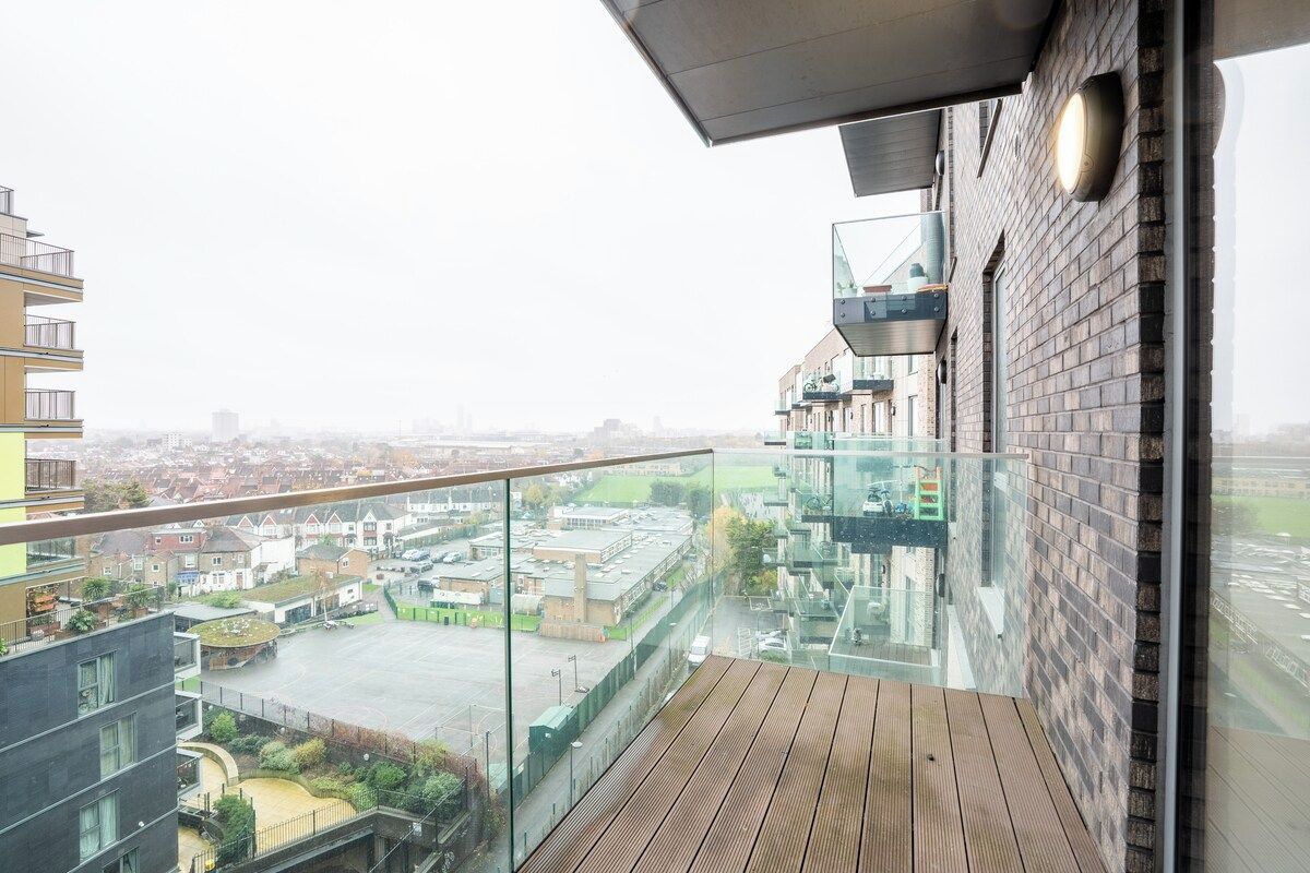 Un edificio moderno con balcón de cristal y vistas a la ciudad.