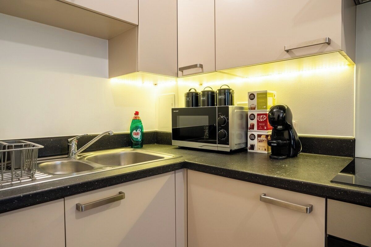 Cocina moderna con microondas, cafetera y termos para té.