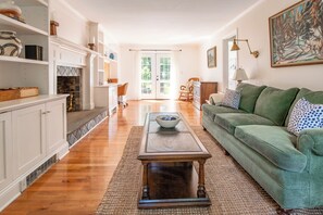 A spacious living room with a green sofa, a coffee table, and a fireplace. - Hollow Spring Retreat--Spacious 5bdr House (Norwalk)