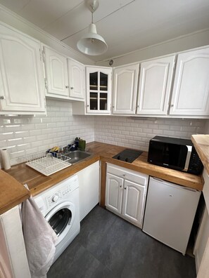 A compact kitchen with white cabinetry, a built-in microwave, a dishwasher, and a washing machine. - New Listing (Boulogne-Billancourt)