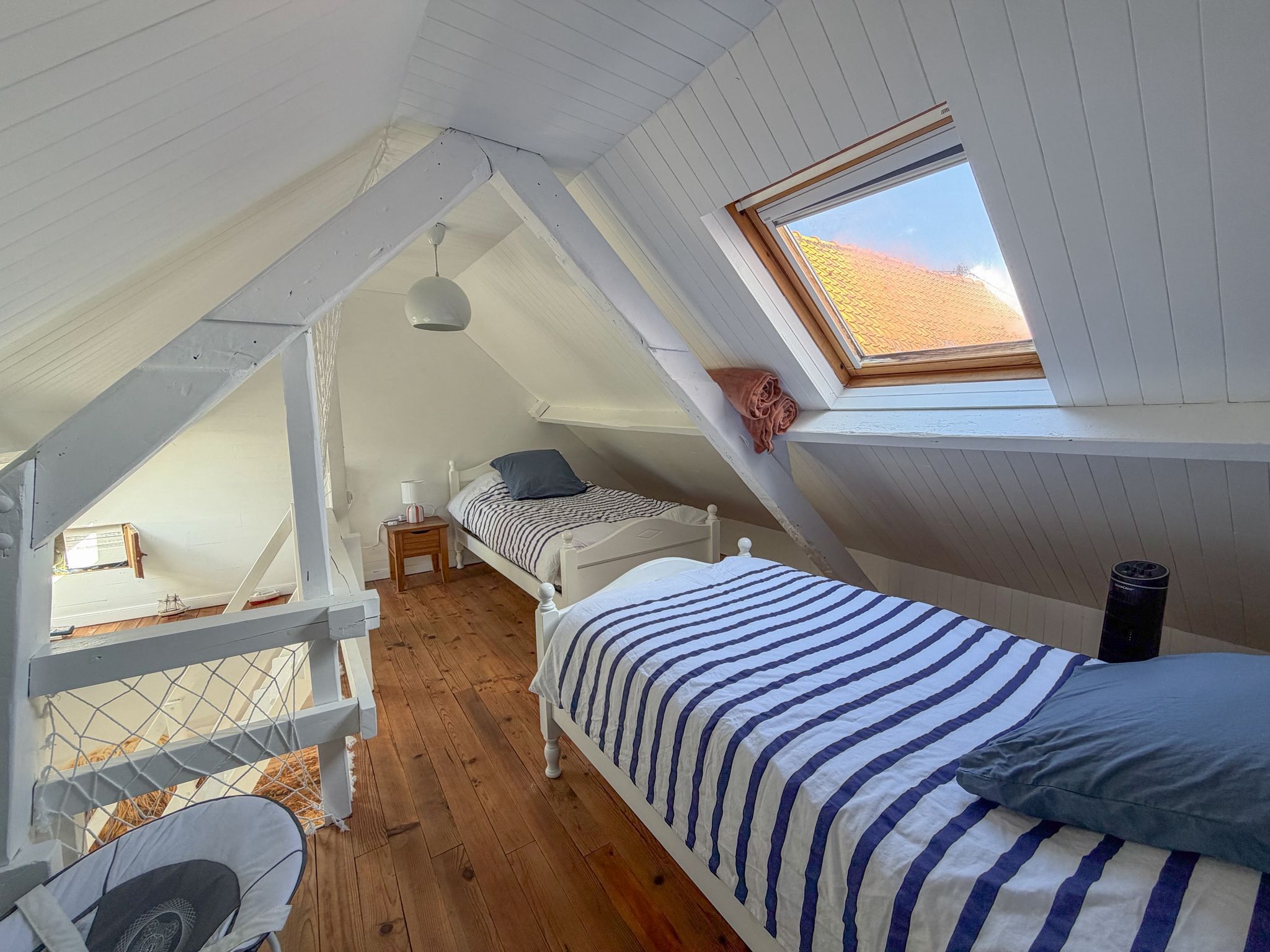 Ein Schlafzimmer im Loft-Stil mit zwei Betten, einem Oberlicht und Holzboden.