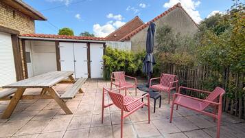 Eine Terrasse mit Picknicktisch, vier Stühlen und Sonnenschirm.