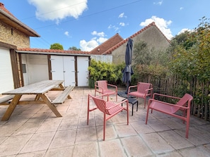 Eine Terrasse mit Picknicktisch, vier Stühlen und Sonnenschirm.