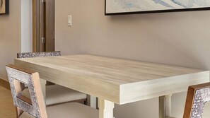 Une table de salle à manger rectangulaire avec un placage en bois clair, accompagnée de quatre chaises au fini vieilli.
