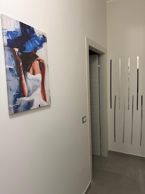 Ein Flur mit einem Gemälde links und vertikalen Linien an der rechten Wand.