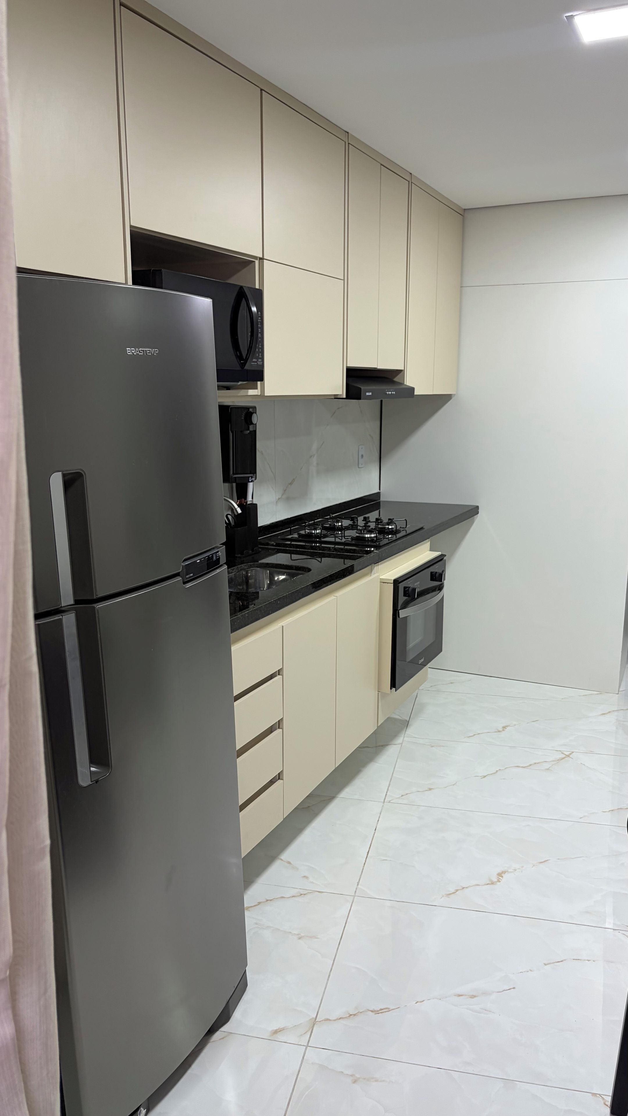 A modern kitchen with a stainless steel refrigerator, a microwave, a gas stove, and a dishwasher.