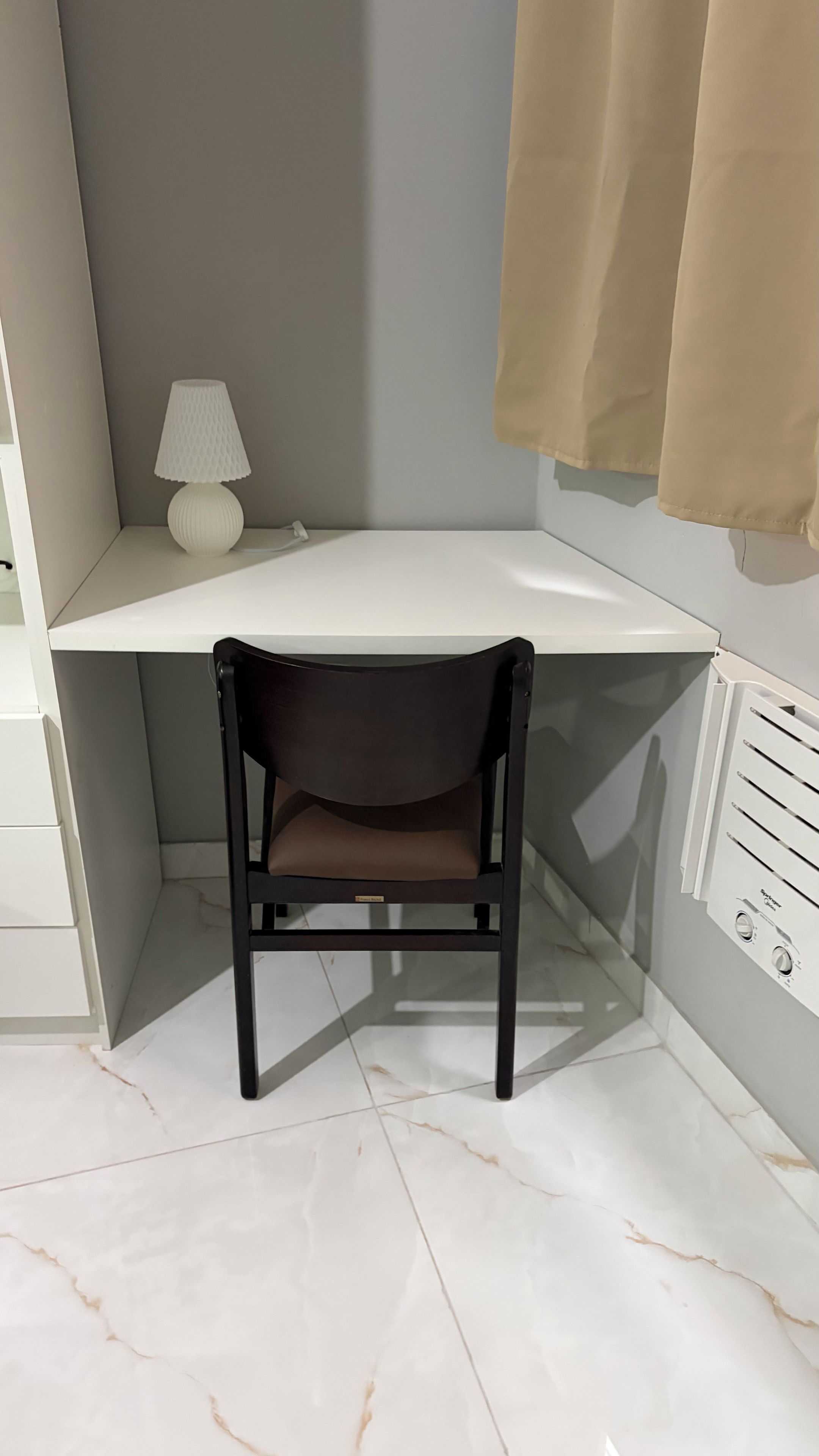 A corner desk with a chair, a lamp, and a radiator.