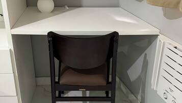 A corner desk with a chair, a lamp, and a radiator.
