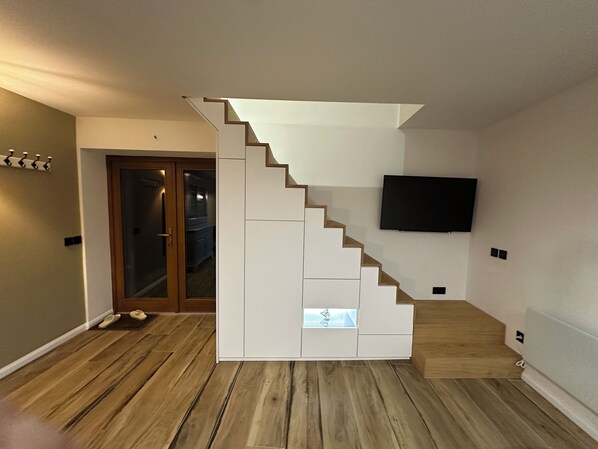 Un escalier au design moderne, un plancher plat et un téléviseur à écran plat fixé au mur.