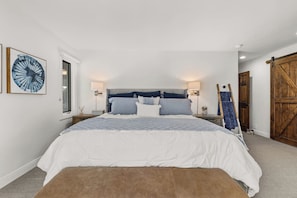 Un dormitorio con una cama grande, una puerta de madera y una obra de arte colgada en la pared.