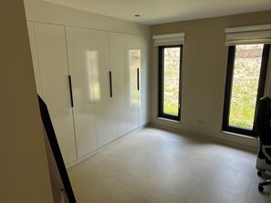 A room with a large wardrobe, two windows with blinds, and a tiled floor. - New Listing (Profondeville)