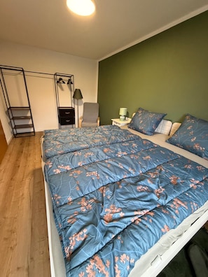 A bedroom with a bed, a chair, a nightstand, a lamp, and a wardrobe. - New Listing (Marienheide)