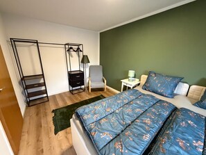 A bedroom with a bed, a chair, a desk, and a wardrobe. - New Listing (Marienheide)