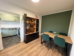 A compact kitchen with a dining area, featuring a wooden table and teal chairs. - New Listing (Marienheide)