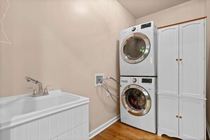 A laundry room with a double washer and dryer, a sink, and a cabinet.