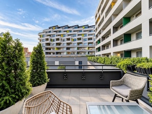 Un immeuble d’appartements moderne doté de nombreux balcons, d’un espace extérieur aménagé et de verdure.