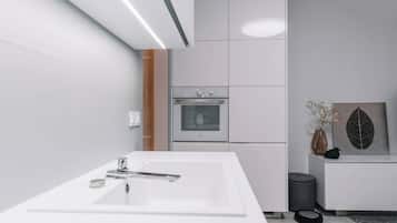 A modern bathroom with a white sink, a built-in oven, and a grey trash bin.