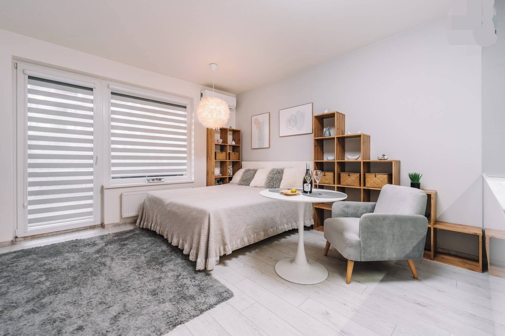 A bedroom with a bed, bedside tables, a chair, a round table, and built-in shelving.