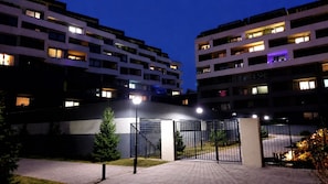 Una entrada porticada a un moderno complejo de apartamentos con varios pisos y ventanas iluminadas.