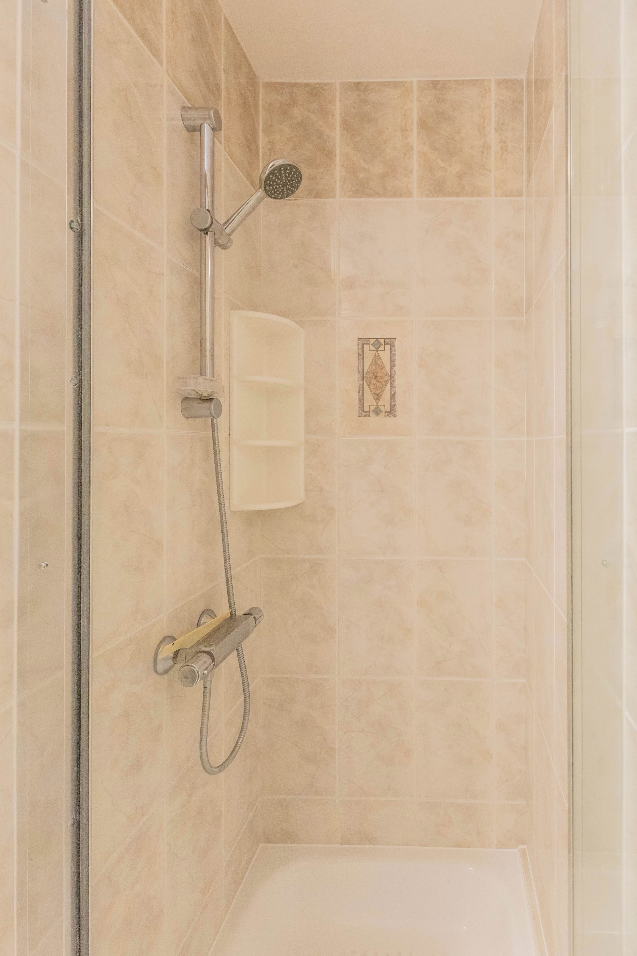 Eine Dusche mit Handbrause und Armaturen an der Wand.