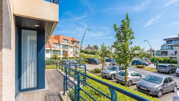 Een woongebouw met een balkon, een parkeerplaats met auto's en een heldere lucht.