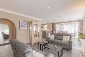 Een moderne woonkamer met een bank, fauteuil en een kast met glazen deuren.