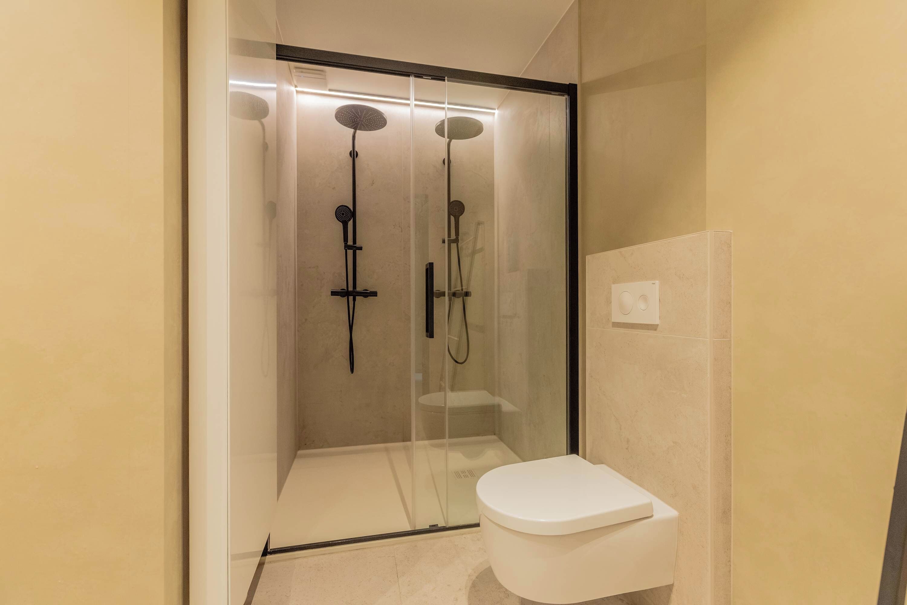 A modern bathroom with a glass-enclosed shower, a white toilet, and a wall-mounted heater.